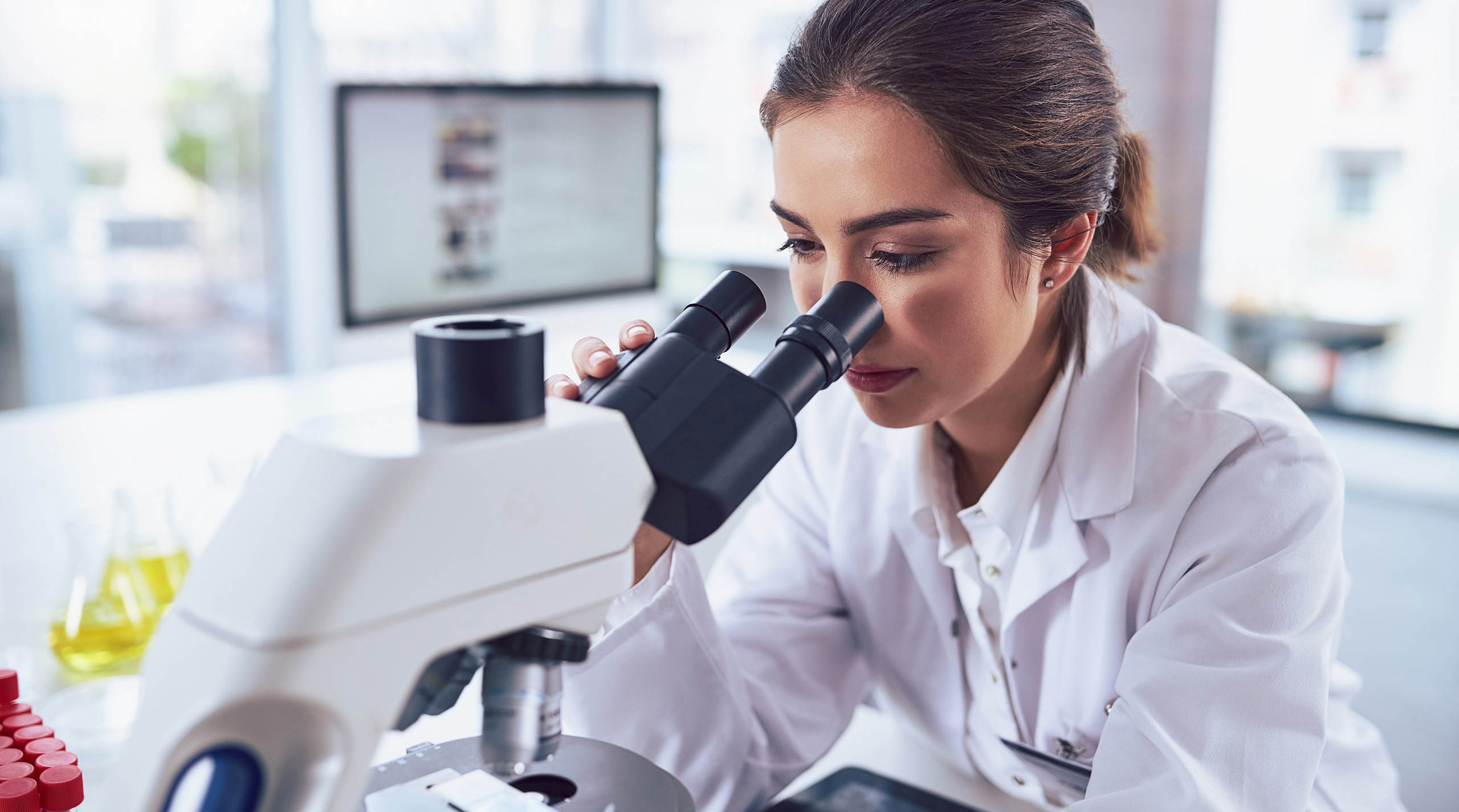 A female scientist looking through a microscope.